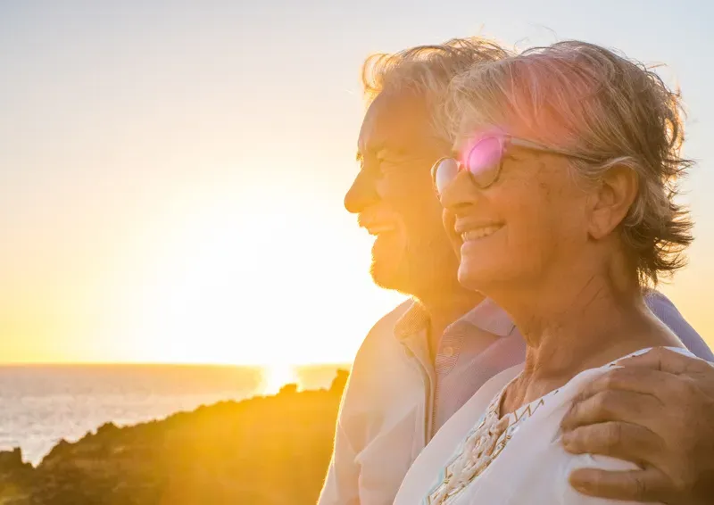 Couple de retraités profitant du coucher de soleil au bord de la mer